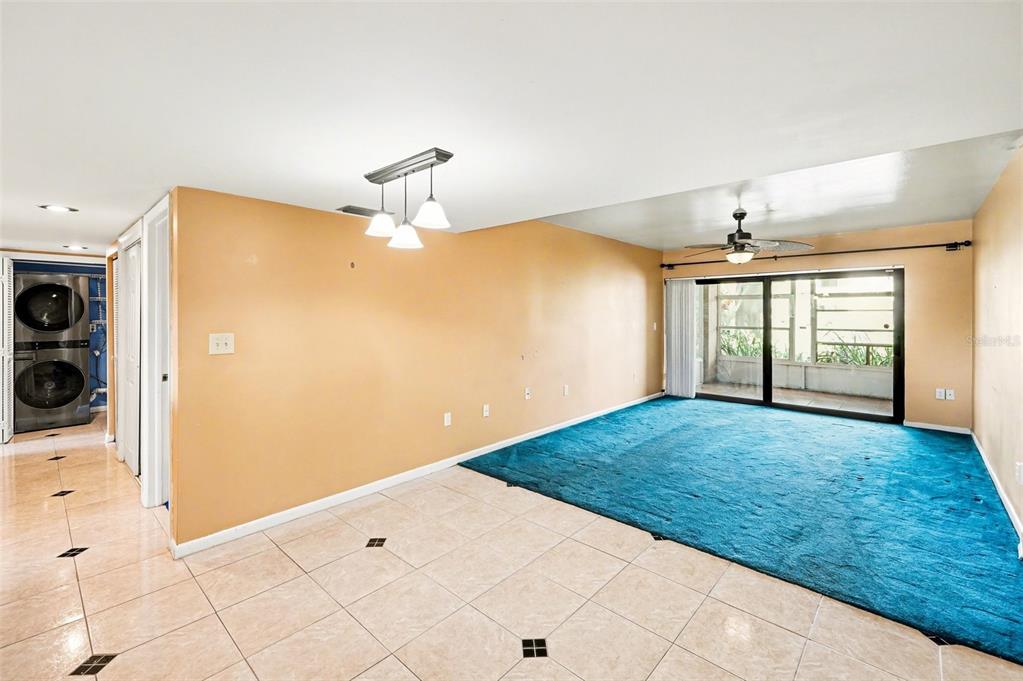 A room features tan walls, a tiled floor, a blue carpeted area, and sliding glass doors — 10755 VILLAGE CLUB CIRCLE N UNIT 101, ST PETERSBURG, FL