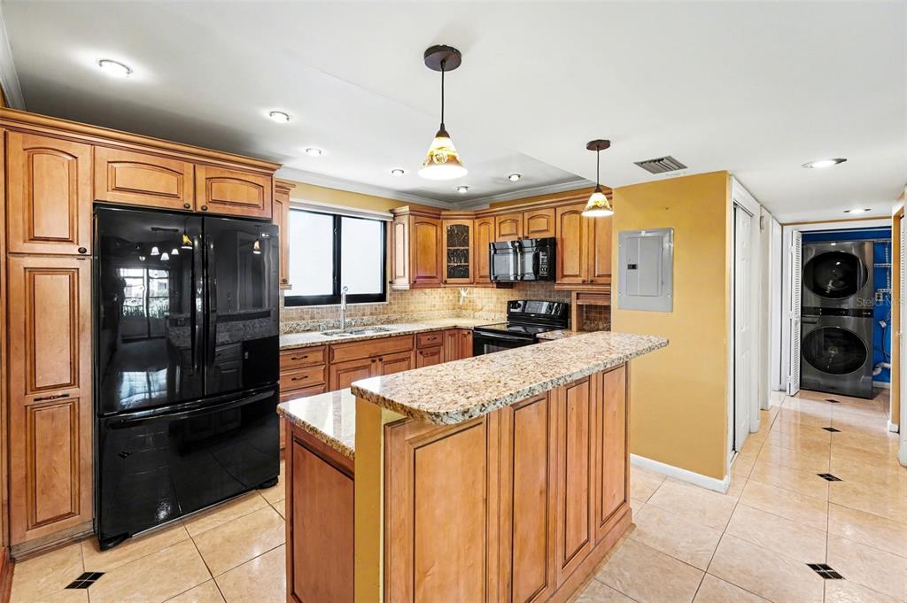 A kitchen with wood cabinets, granite countertops, black appliances, and tile flooring — 10755 VILLAGE CLUB CIRCLE N UNIT 101, ST PETERSBURG, FL
