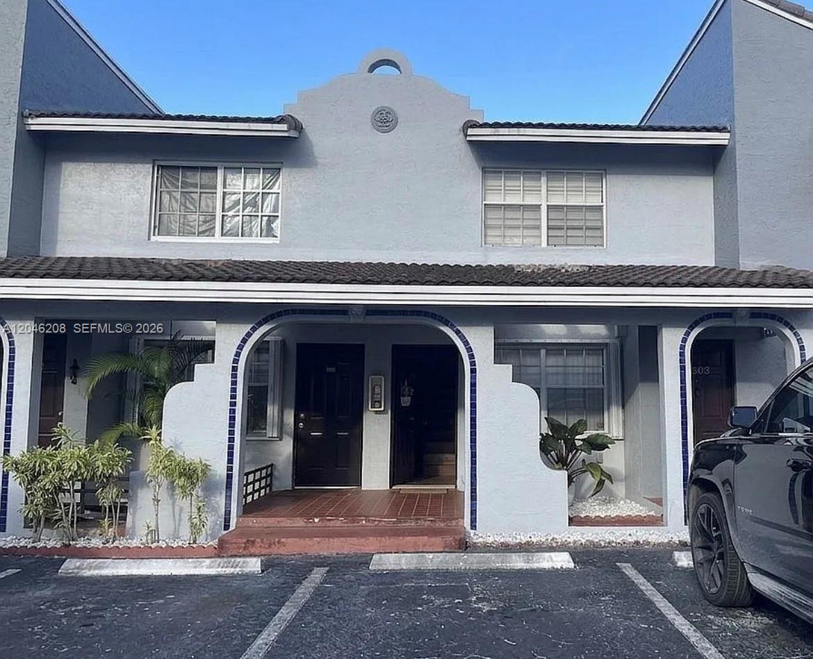 The exterior of a two-story gray stucco townhouse features arched entryways and a tiled roof — 7100 NW 173rd Dr # 1304, Hialeah FL 33015, HIALEAH, FL