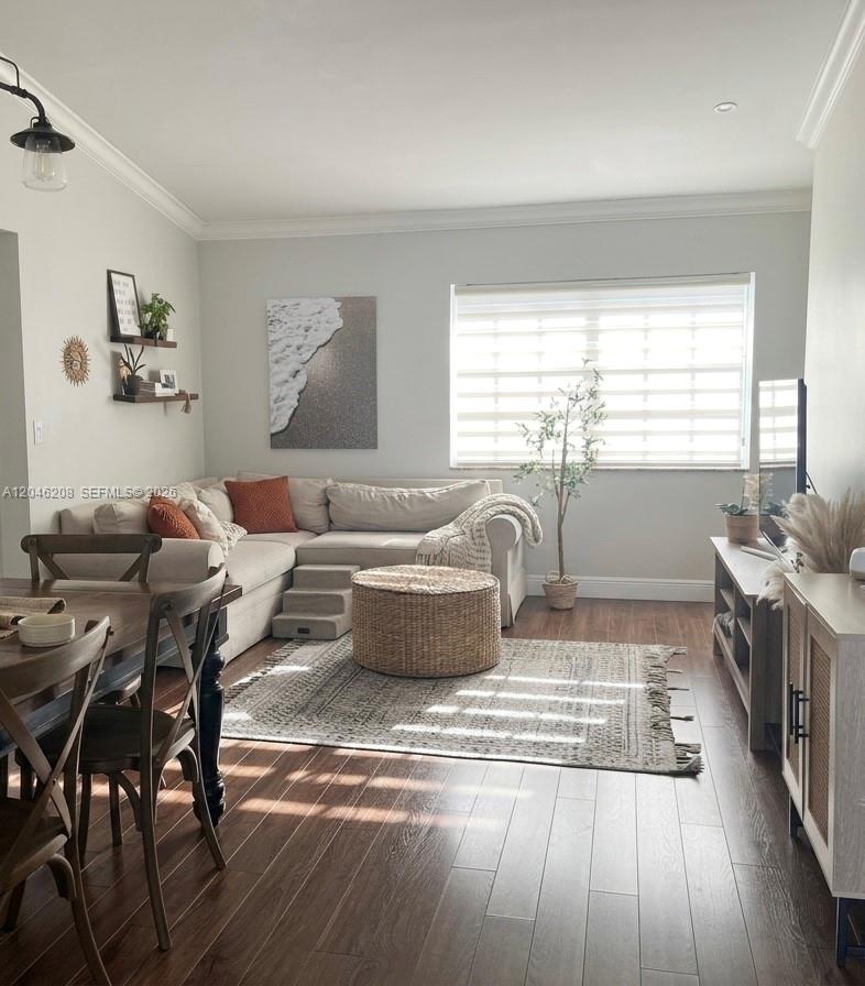 A living room features a beige sectional sofa, a woven ottoman, and wood-look flooring — 7100 NW 173rd Dr # 1304, Hialeah FL 33015, HIALEAH, FL