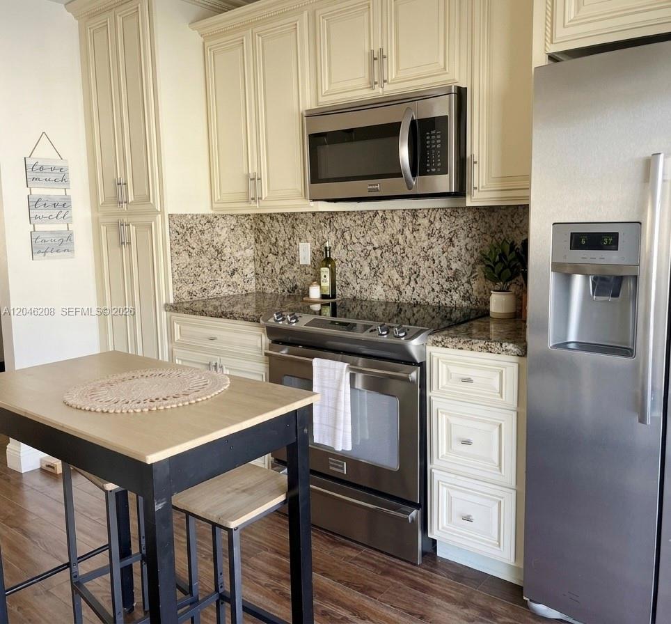 A kitchen features cream cabinets, granite countertops, stainless steel appliances, and a small wooden island — 7100 NW 173rd Dr # 1304, Hialeah FL 33015, HIALEAH, FL