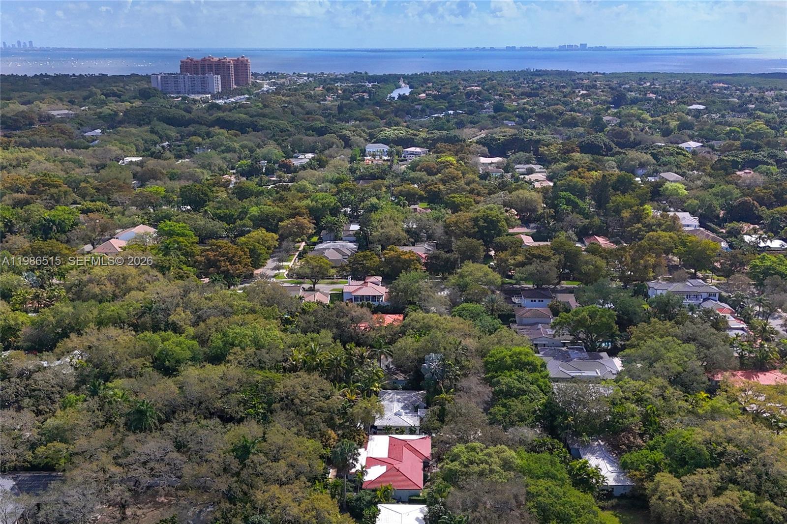 An aerial view shows a dense, tree-filled residential neighborhood near a large body of water — 731 San Juan Dr, Coral Gables FL 33143, CORAL GABLES, FL