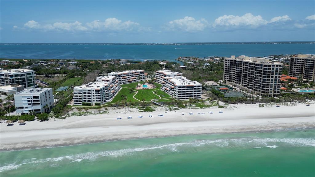 An aerial view of beachfront condominium buildings with a central courtyard and swimming pool — 1425 GULF OF MEXICO DRIVE UNIT 408, LONGBOAT KEY, FL