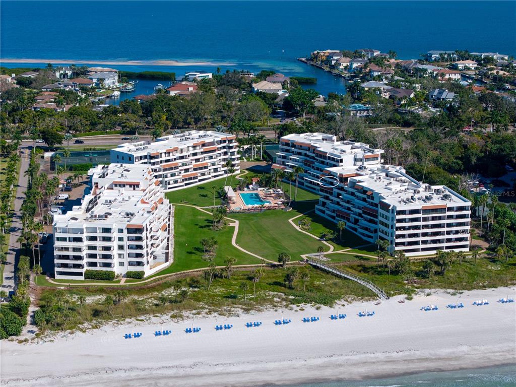 An aerial view shows three multi-story residential buildings surrounding a central pool and lawn area — 1425 GULF OF MEXICO DRIVE UNIT 408, LONGBOAT KEY, FL