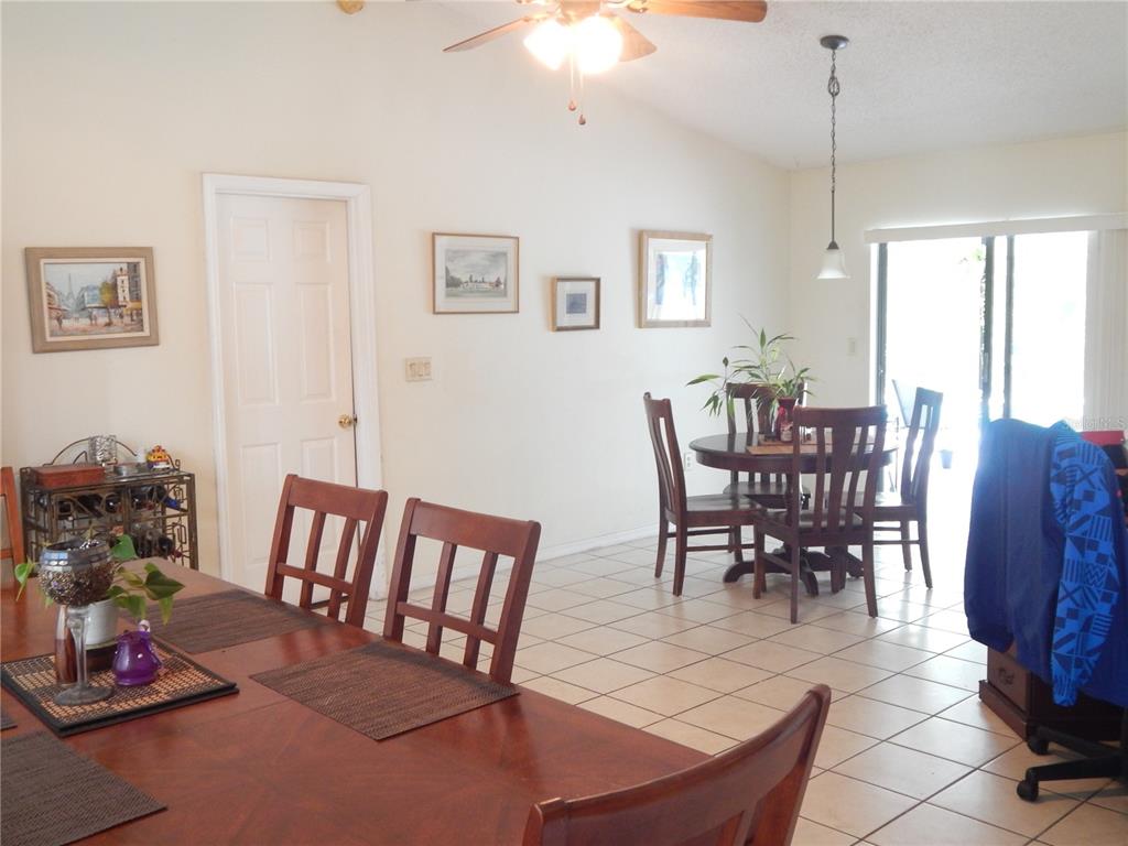 A dining area with tile floors, a wooden table, and a sliding glass door — 4109 CANNON COURT, KISSIMMEE, FL
