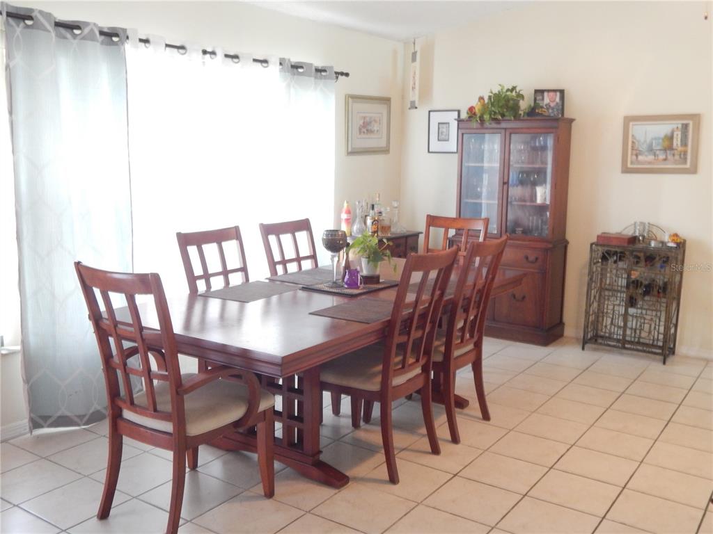 A dining room features a wooden table with six chairs, a hutch, and tiled flooring — 4109 CANNON COURT, KISSIMMEE, FL