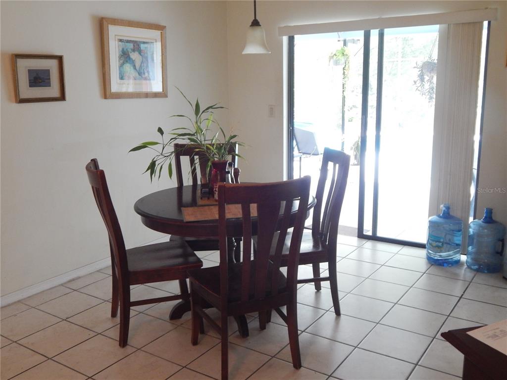 A dining area features a round wooden table, four chairs, tile flooring, and sliding doors — 4109 CANNON COURT, KISSIMMEE, FL