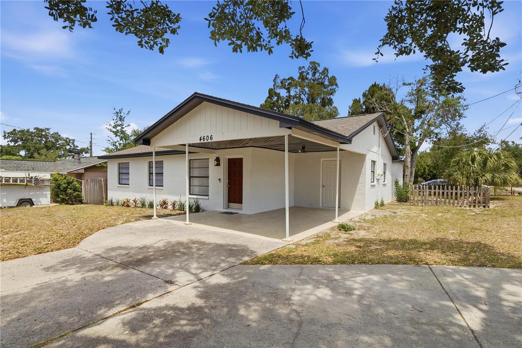 A white single-story house features a front carport, a red door, and a concrete driveway — 4606 E LINEBAUGH AVENUE, TAMPA, FL