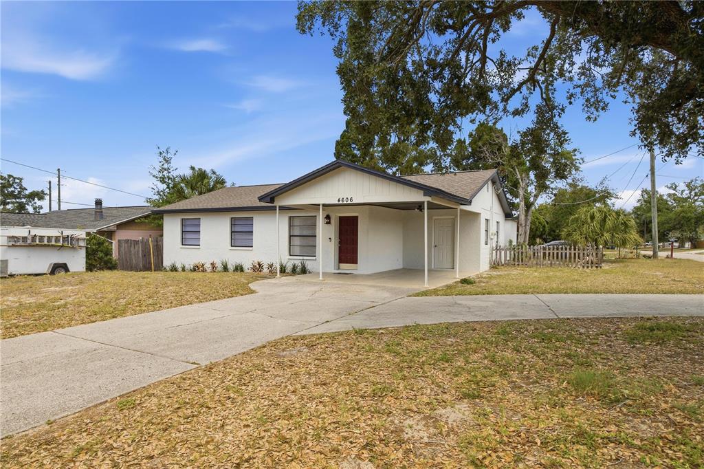 A single-story house with a white exterior, a carport, and a red front door — 4606 E LINEBAUGH AVENUE, TAMPA, FL