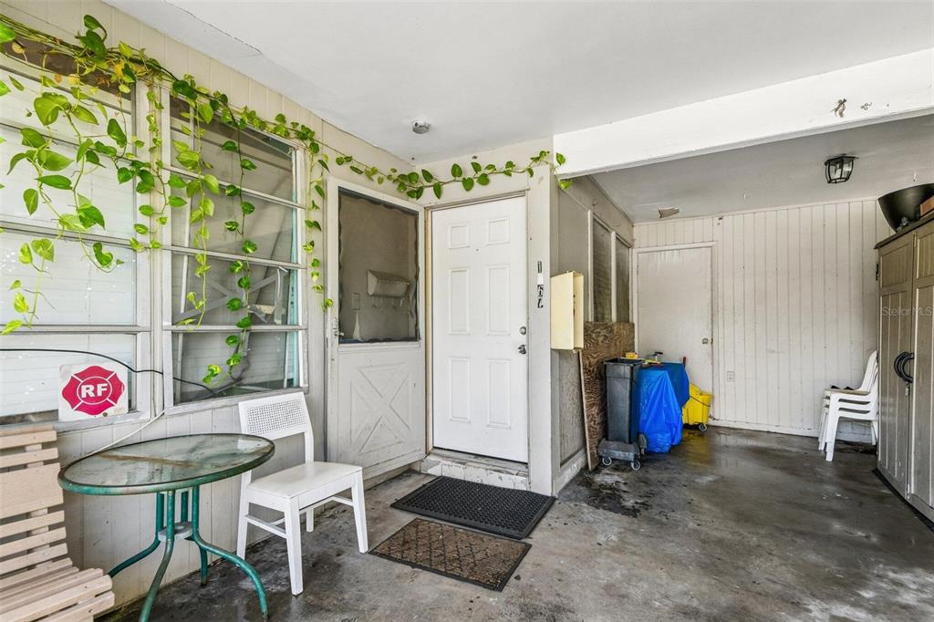 A covered patio area features a white front door, a small table, and potted vines — 1267 FRANKLIN STREET, CLEARWATER, FL