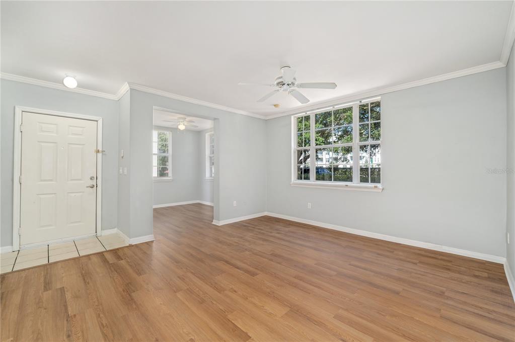 An empty living room features light blue walls, wood-look flooring, and a large window — 714 SIENA PALM DRIVE UNIT 104, CELEBRATION, FL