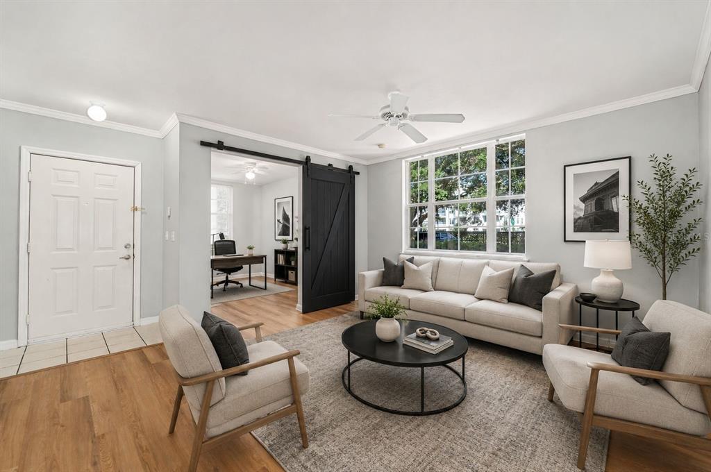 A living room with light gray walls, a beige sofa, two armchairs, and a sliding barn door — 714 SIENA PALM DRIVE UNIT 104, CELEBRATION, FL