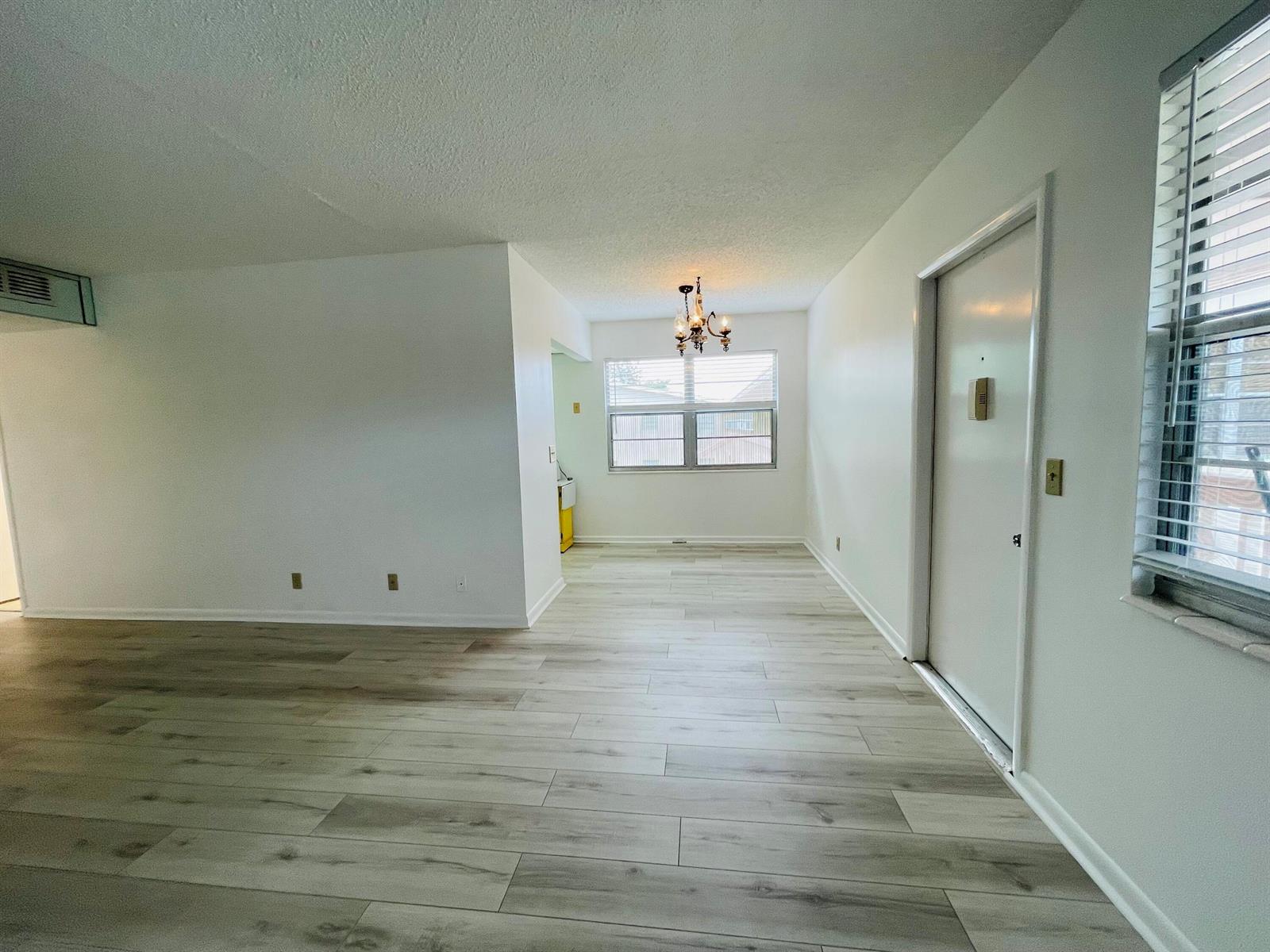 A bright dining area features light wood-look flooring, white walls, and a hanging chandelier — 333 Farnham P, Deerfield Beach FL 33442, DEERFIELD BEACH, FL