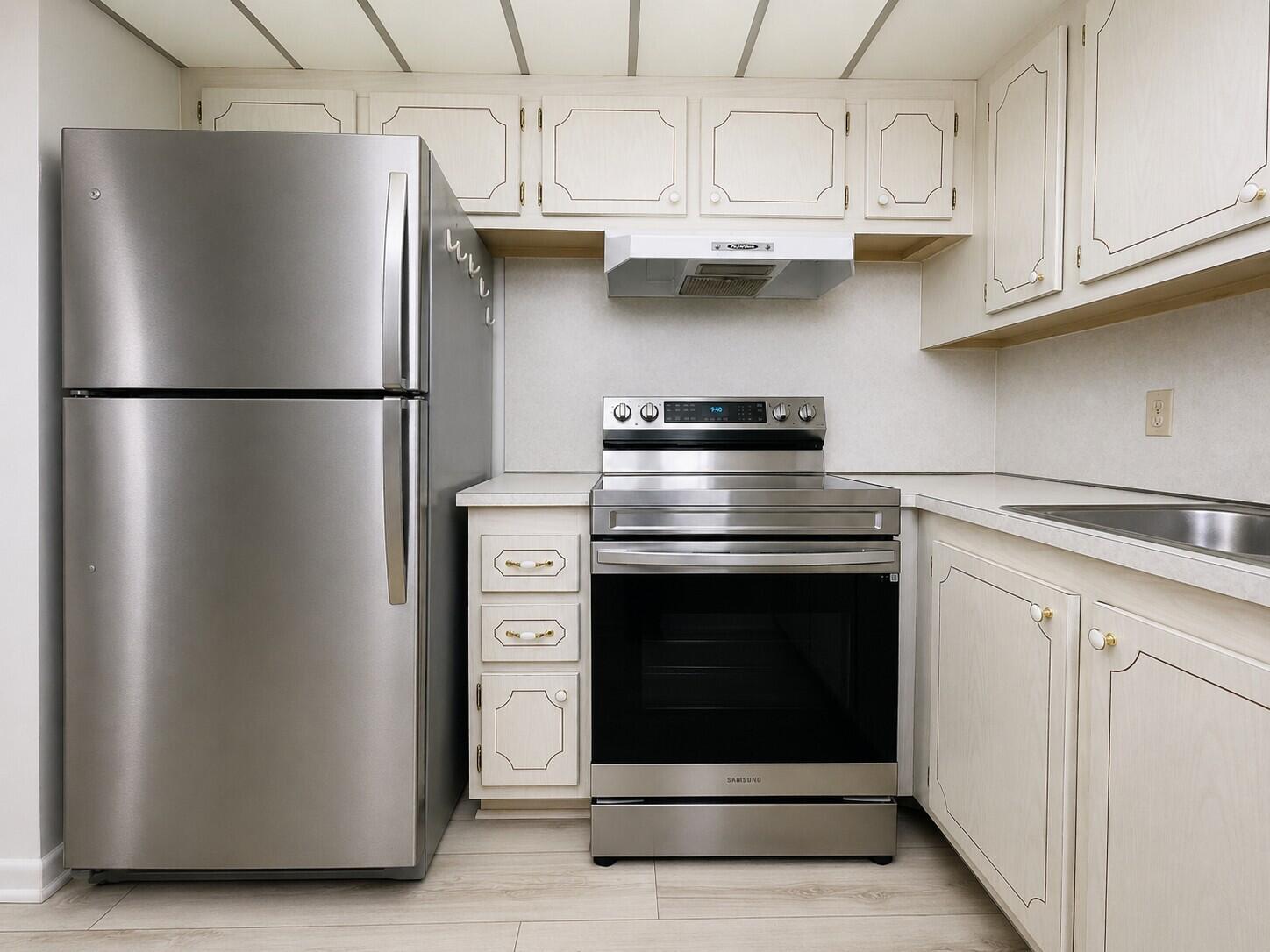 A kitchen featuring stainless steel appliances, light-colored cabinetry, and a white range hood — 333 Farnham P, Deerfield Beach FL 33442, DEERFIELD BEACH, FL