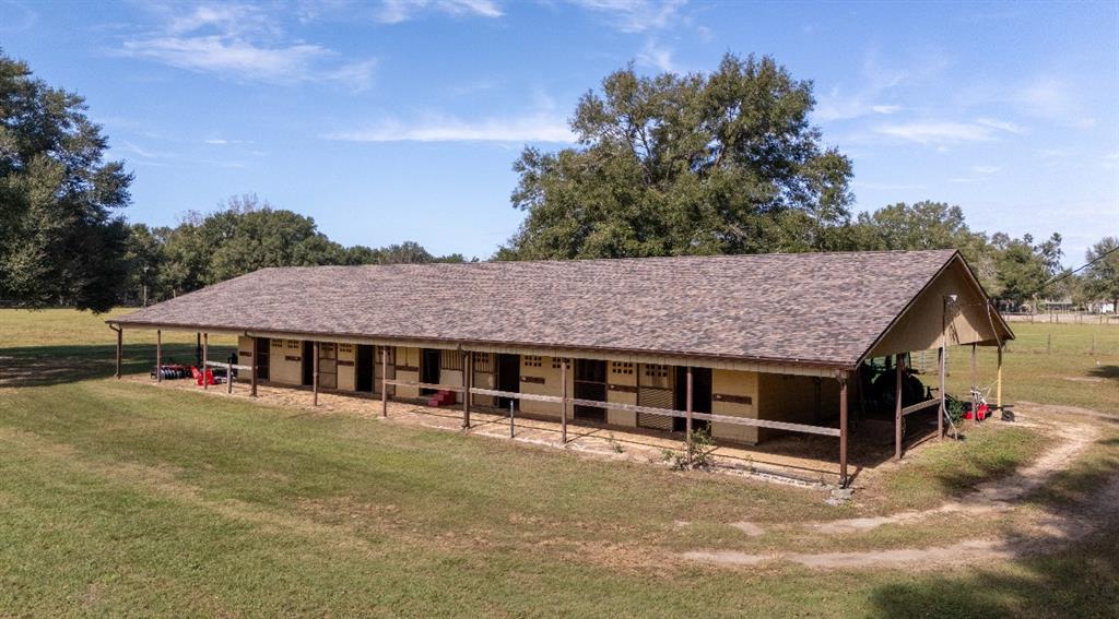 An aerial view of a long, single-story horse stable with a shingled roof and stalls — 1801 NE 77TH STREET, OCALA, FL
