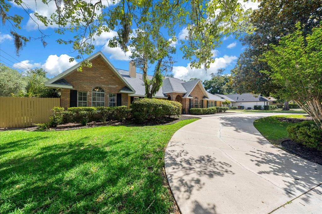 A brick house with a long concrete driveway and a large front lawn — 2420 SE 15TH STREET, OCALA, FL