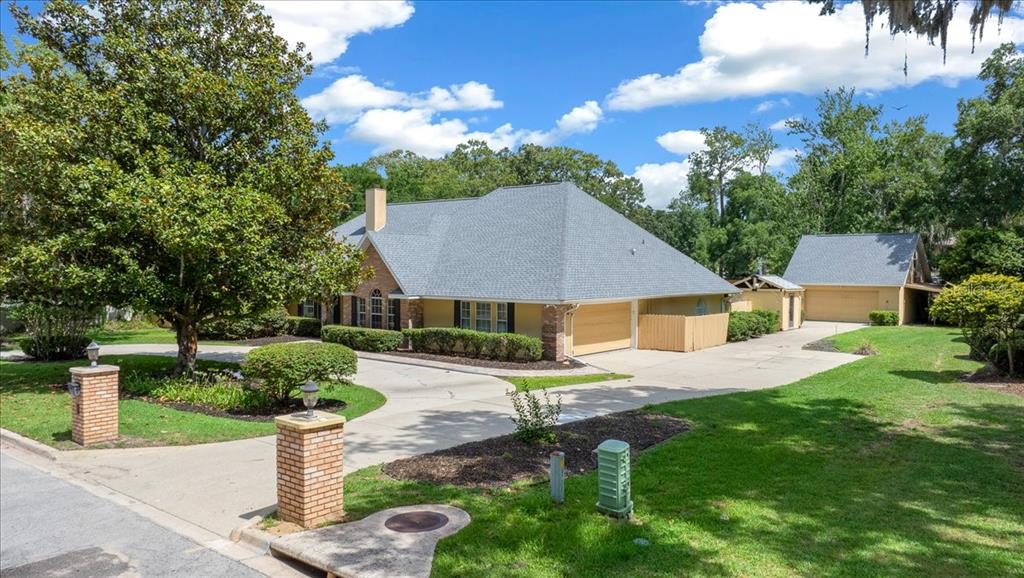A single-story house with a gray roof, tan siding, and a detached garage — 2420 SE 15TH STREET, OCALA, FL