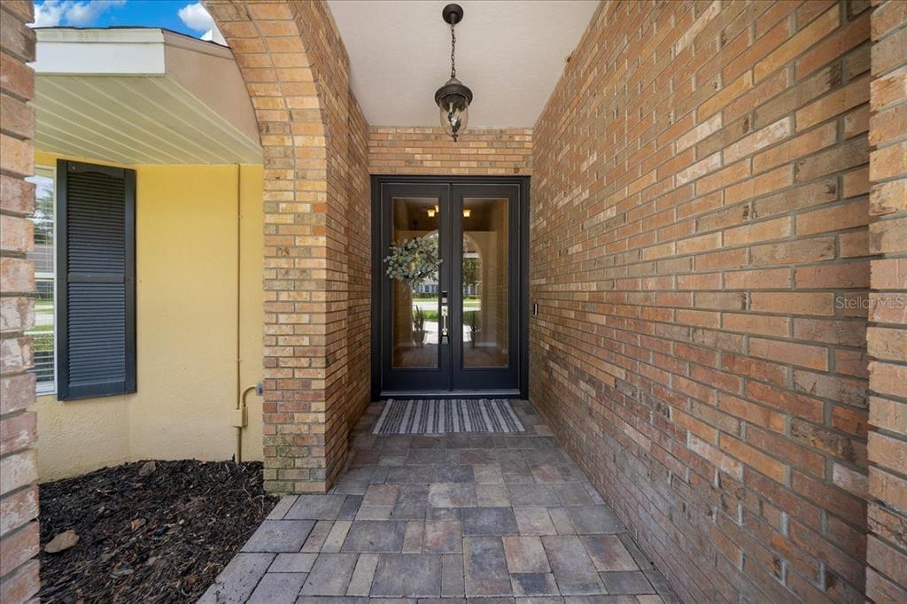 A brick-walled entryway features a double glass front door and stone paver flooring — 2420 SE 15TH STREET, OCALA, FL