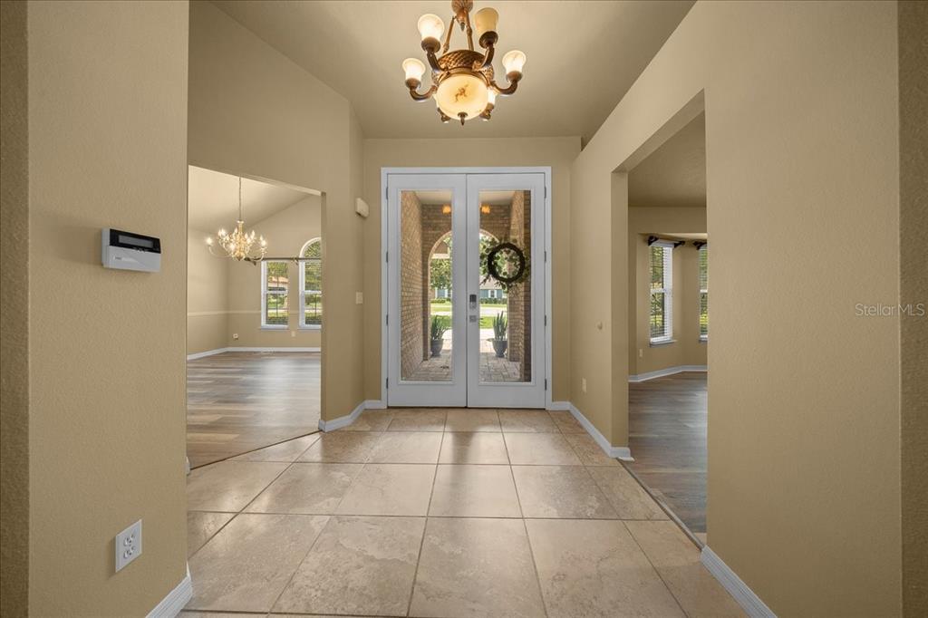 A tiled entryway features double glass front doors, a chandelier, and arched room openings — 2420 SE 15TH STREET, OCALA, FL