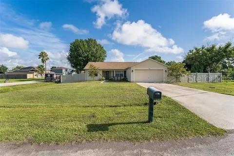 A single-story house with a tan exterior and a two-car garage sits on a lawn — 502 MATTERHORN PLACE, KISSIMMEE, FL