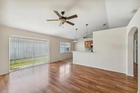 A living room with wood flooring, a ceiling fan, and a sliding glass door — 502 MATTERHORN PLACE, KISSIMMEE, FL