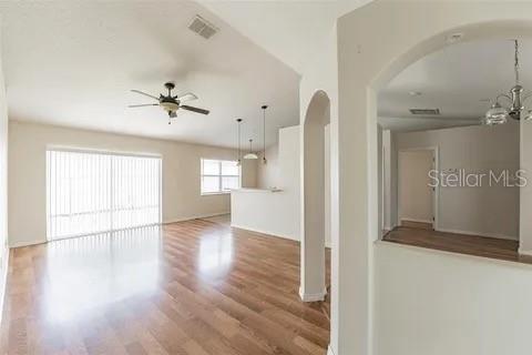 An interior view showing a living area with wood floors, a ceiling fan, and archways — 502 MATTERHORN PLACE, KISSIMMEE, FL