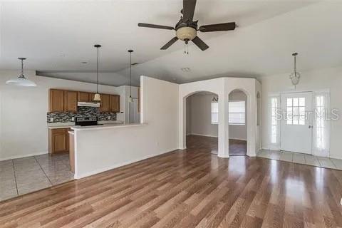 An open-concept living area features wood flooring, a kitchen with wooden cabinets, and a ceiling fan — 502 MATTERHORN PLACE, KISSIMMEE, FL