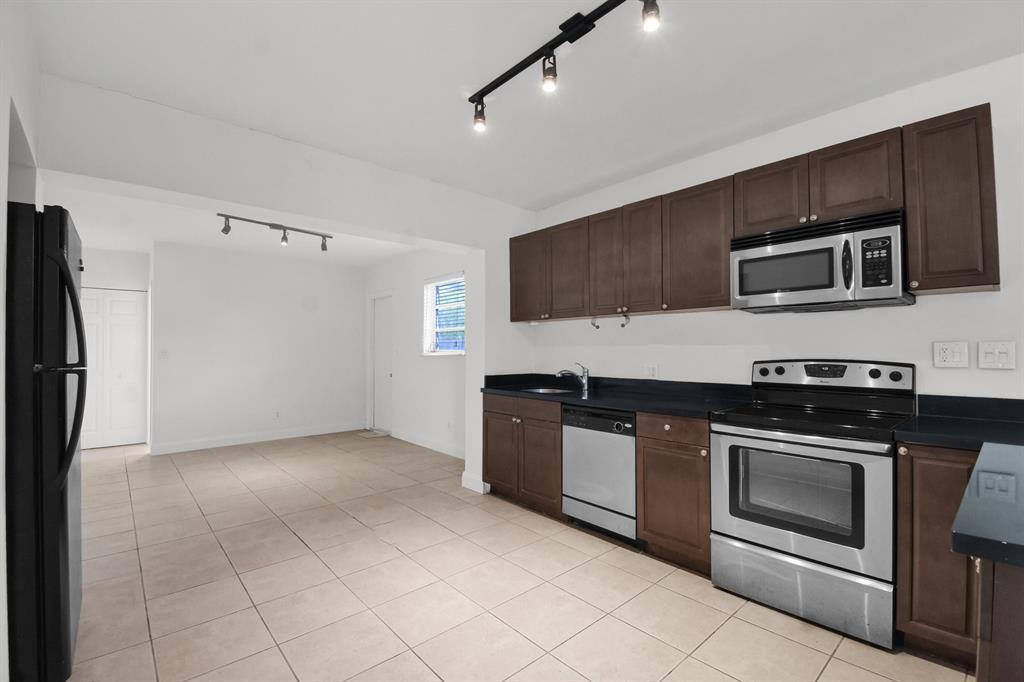 A kitchen with dark wood cabinets, stainless steel appliances, and light tile flooring — 1116 S 17th Avenue S, Hollywood FL 33020, HOLLYWOOD, FL