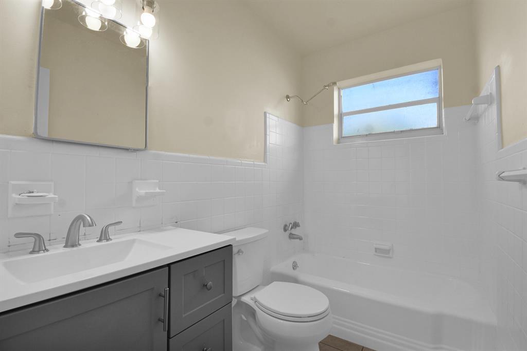 A bathroom with a gray vanity, white tiled walls, a toilet, and a shower-tub combo — 1116 S 17th Avenue S, Hollywood FL 33020, HOLLYWOOD, FL