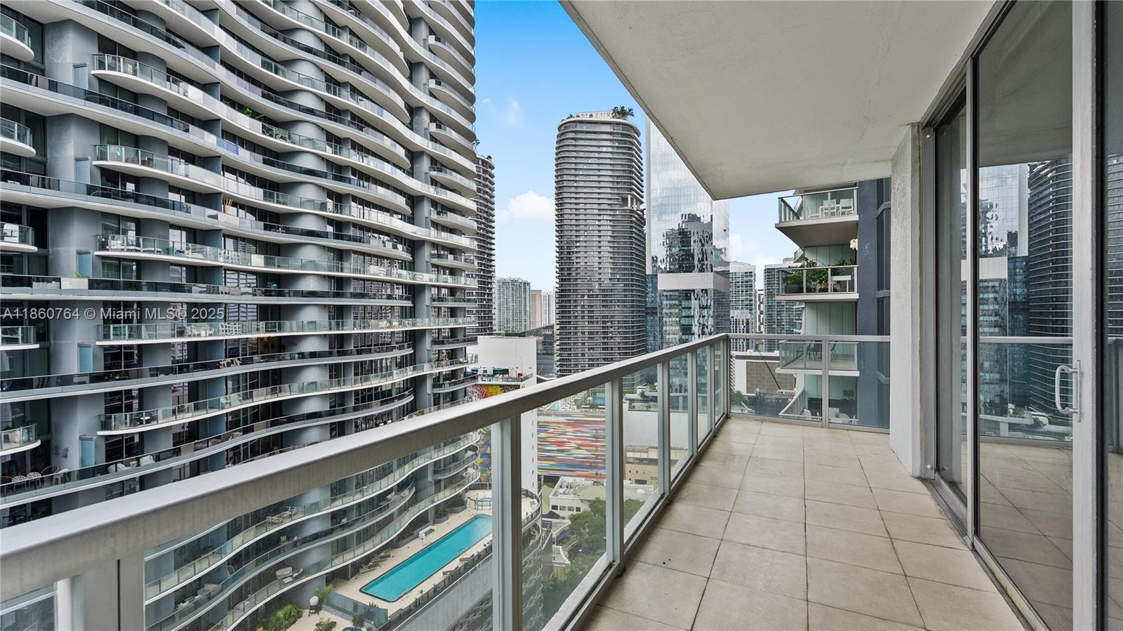 A balcony with tile flooring overlooks a swimming pool and surrounding high-rise apartment buildings — 1050 Brickell Ave # 2620, Miami FL 33131, MIAMI, FL