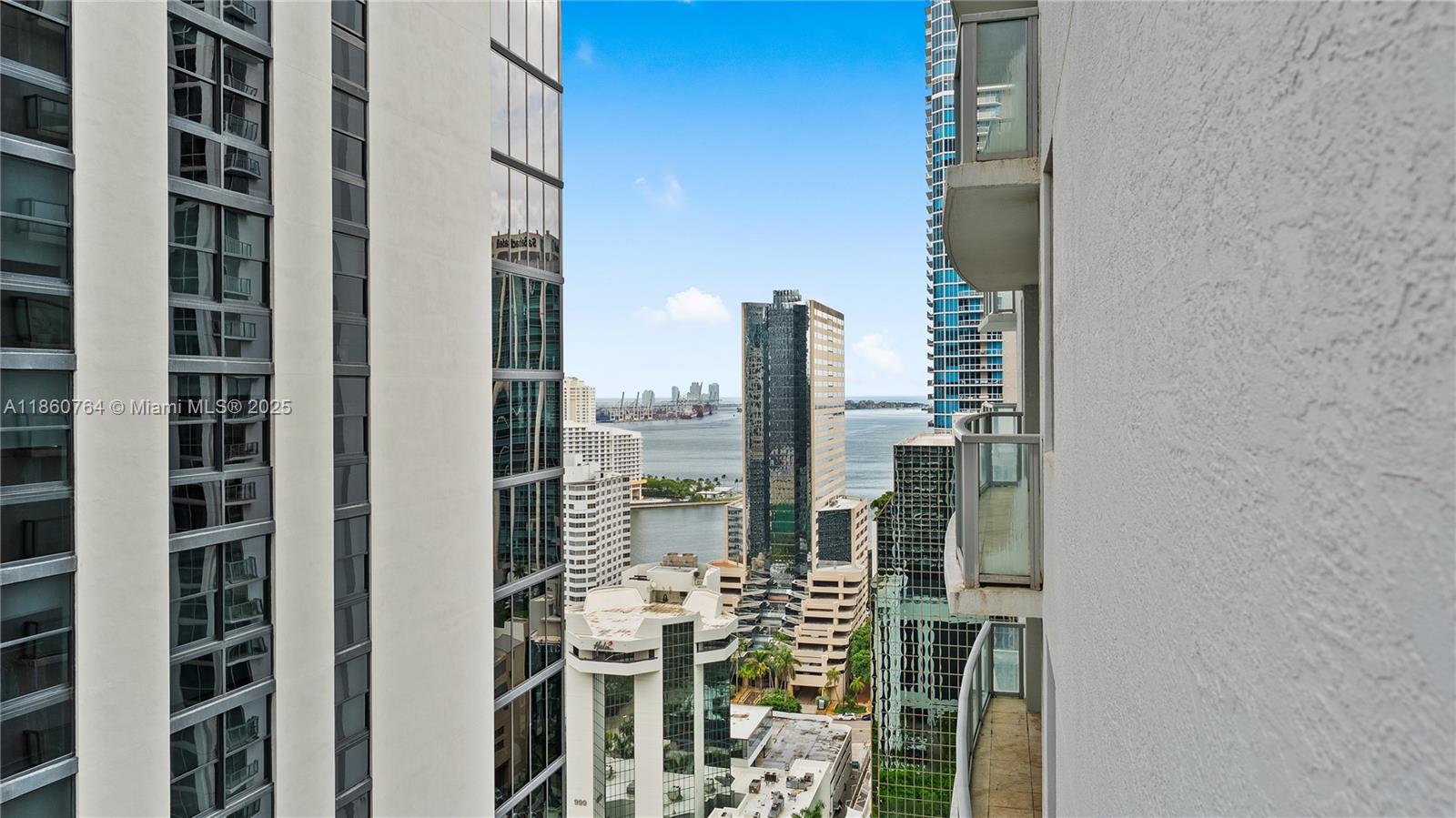 A high-rise balcony view overlooks a city skyline, harbor, and distant ocean — 1050 Brickell Ave # 2620, Miami FL 33131, MIAMI, FL