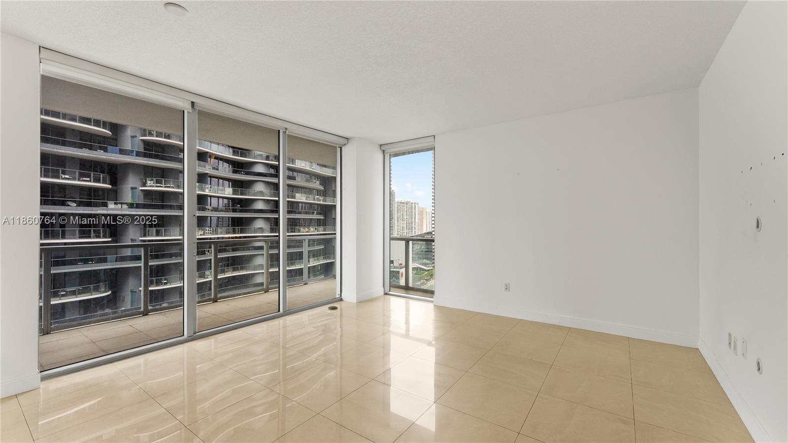 An empty room features large floor-to-ceiling windows, light tile flooring, and white walls — 1050 Brickell Ave # 2620, Miami FL 33131, MIAMI, FL