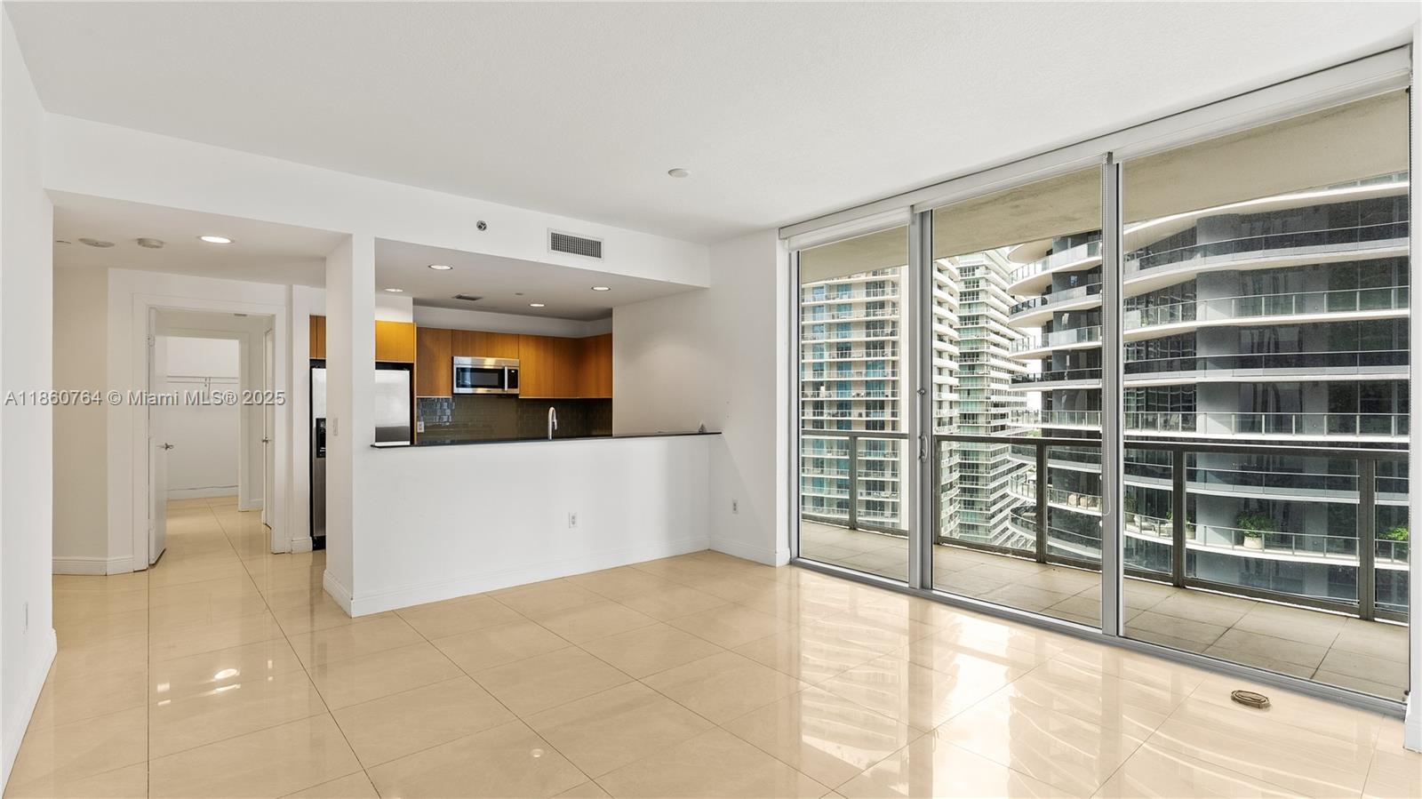 An open-concept living area features light tile flooring, a kitchen pass-through, and floor-to-ceiling windows — 1050 Brickell Ave # 2620, Miami FL 33131, MIAMI, FL