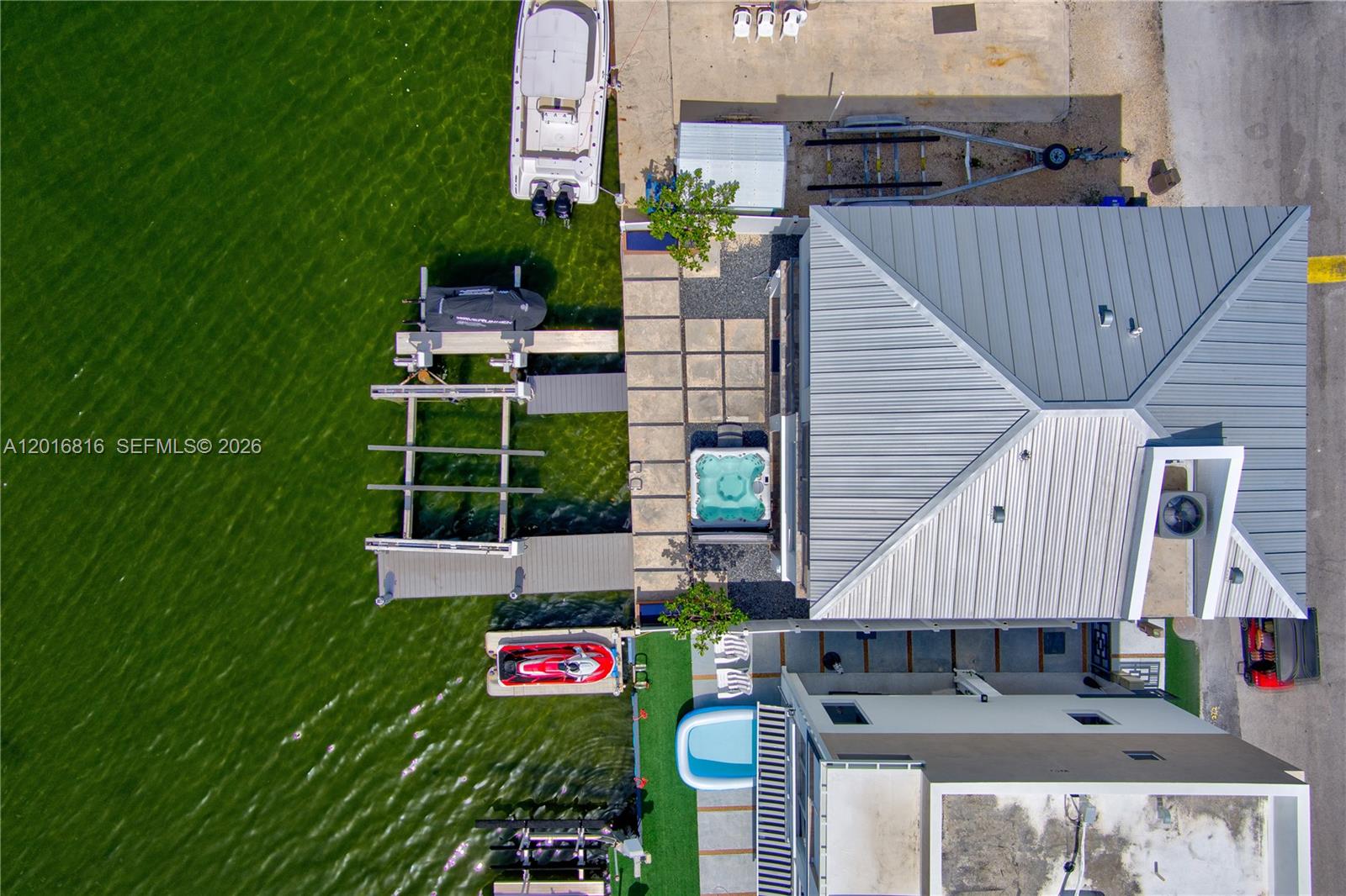 An aerial view shows a waterfront property with a boat dock, jet skis, and hot tub — 325 Calusa, Key Largo FL 33037, KEY LARGO, FL