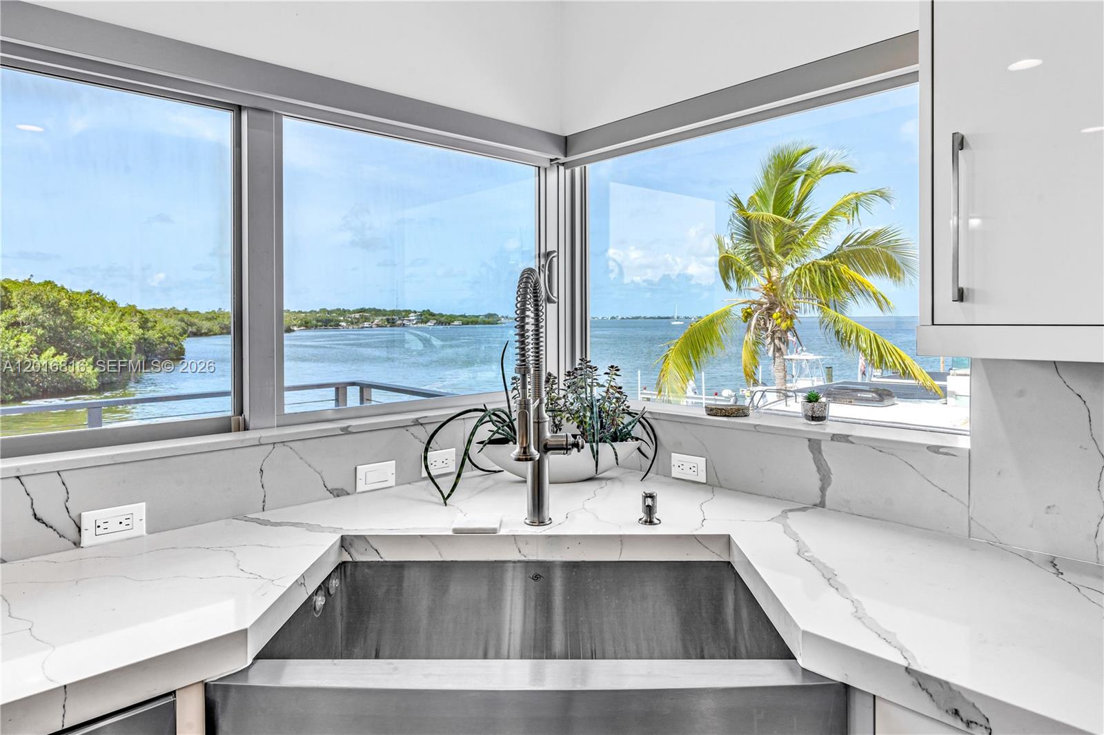 A kitchen sink with a view of the water and a palm tree outside — 325 Calusa, Key Largo FL 33037, KEY LARGO, FL