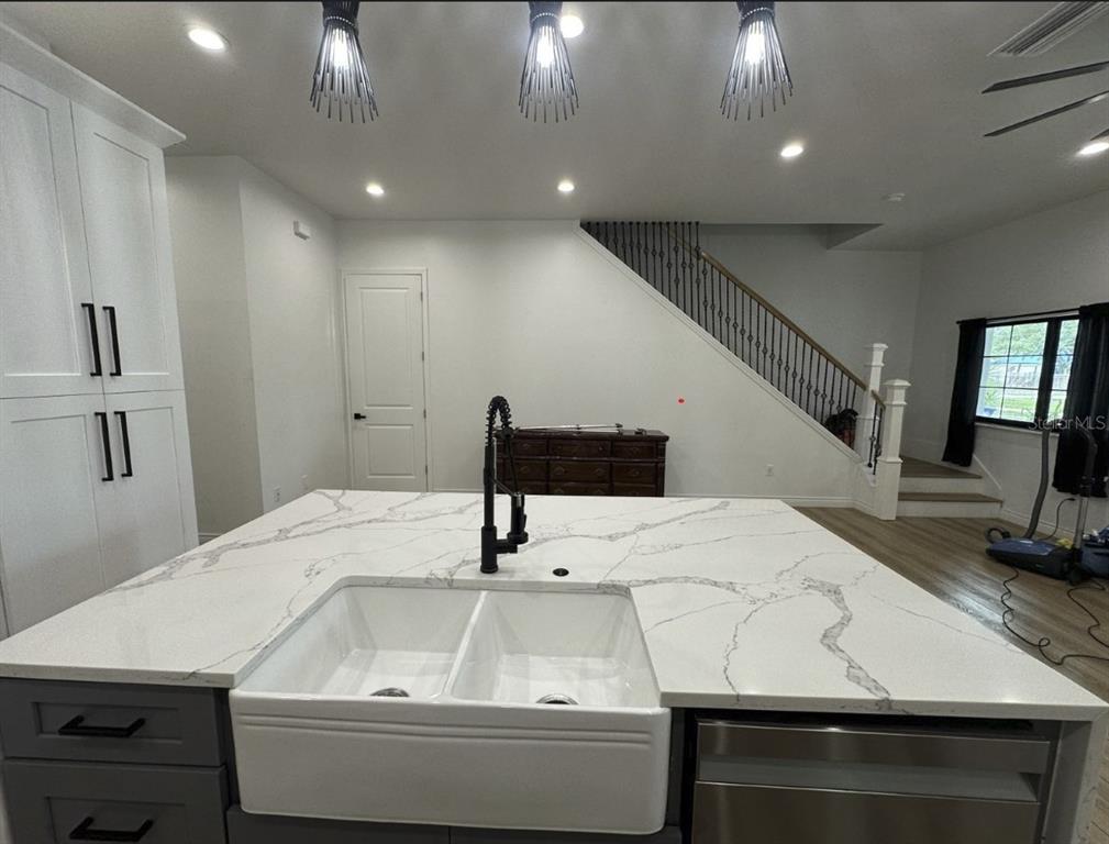 A kitchen island with a farmhouse sink and white countertops sits before a staircase — 319 W WEST STREET, TAMPA, FL