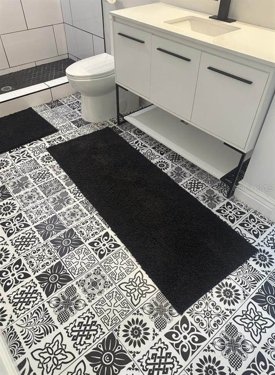 A bathroom features a white vanity, a toilet, and patterned black and white floor tiles — 319 W WEST STREET, TAMPA, FL