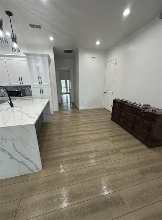 A kitchen with a white marble island, white cabinetry, and wood-look flooring — 319 W WEST STREET, TAMPA, FL