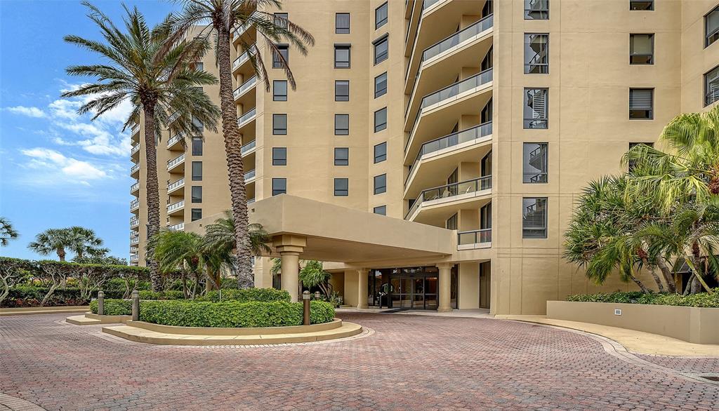 A paved driveway leads to the entrance of a multi-story tan apartment building — 1281 GULF OF MEXICO DRIVE UNIT 111, LONGBOAT KEY, FL