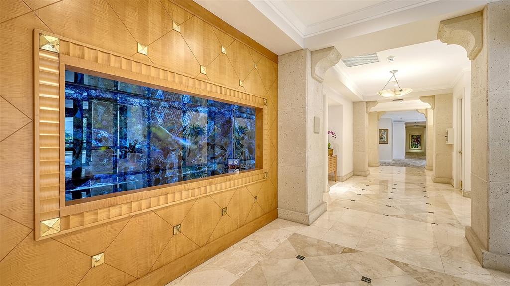 A hallway features a large built-in aquarium set into a wood-paneled wall with marble flooring — 1281 GULF OF MEXICO DRIVE UNIT 111, LONGBOAT KEY, FL