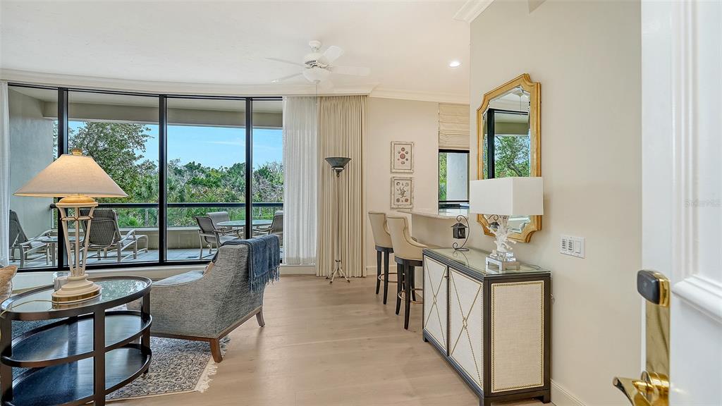 A bright living area features light wood floors, a balcony, and a breakfast bar — 1281 GULF OF MEXICO DRIVE UNIT 111, LONGBOAT KEY, FL