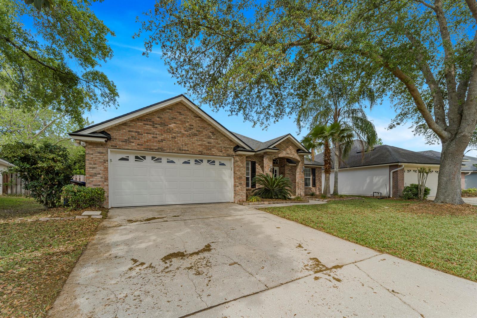 A brick single-story house with a two-car garage and a concrete driveway under large trees — 908 W Doty Branch Lane, FL 32259, FL