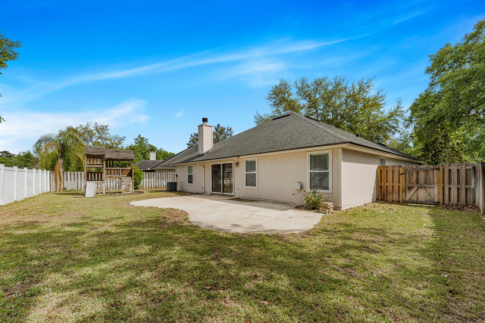 The backyard features a concrete patio, a wooden playset, and a fenced-in lawn — 908 W Doty Branch Lane, FL 32259, FL
