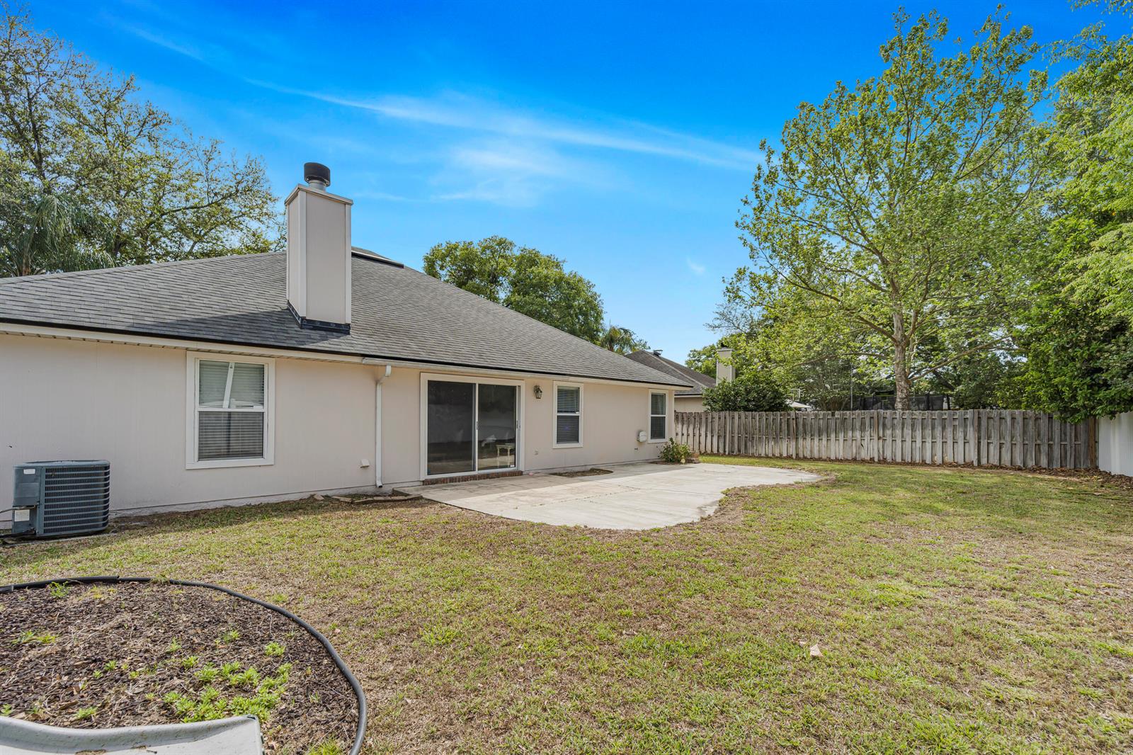 The exterior of a single-story house features a concrete patio, a chimney, and a fence — 908 W Doty Branch Lane, FL 32259, FL
