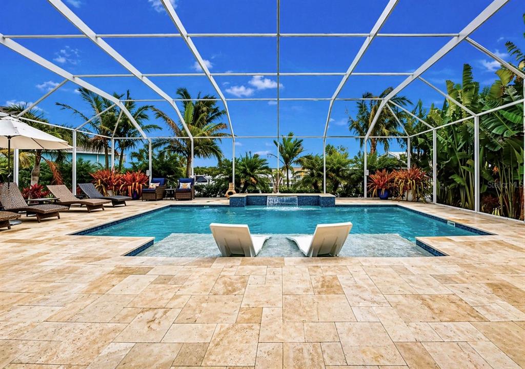 A screened-in swimming pool with a sun shelf and stone patio under a blue sky — 954 SIGNET DRIVE, APOLLO BEACH, FL