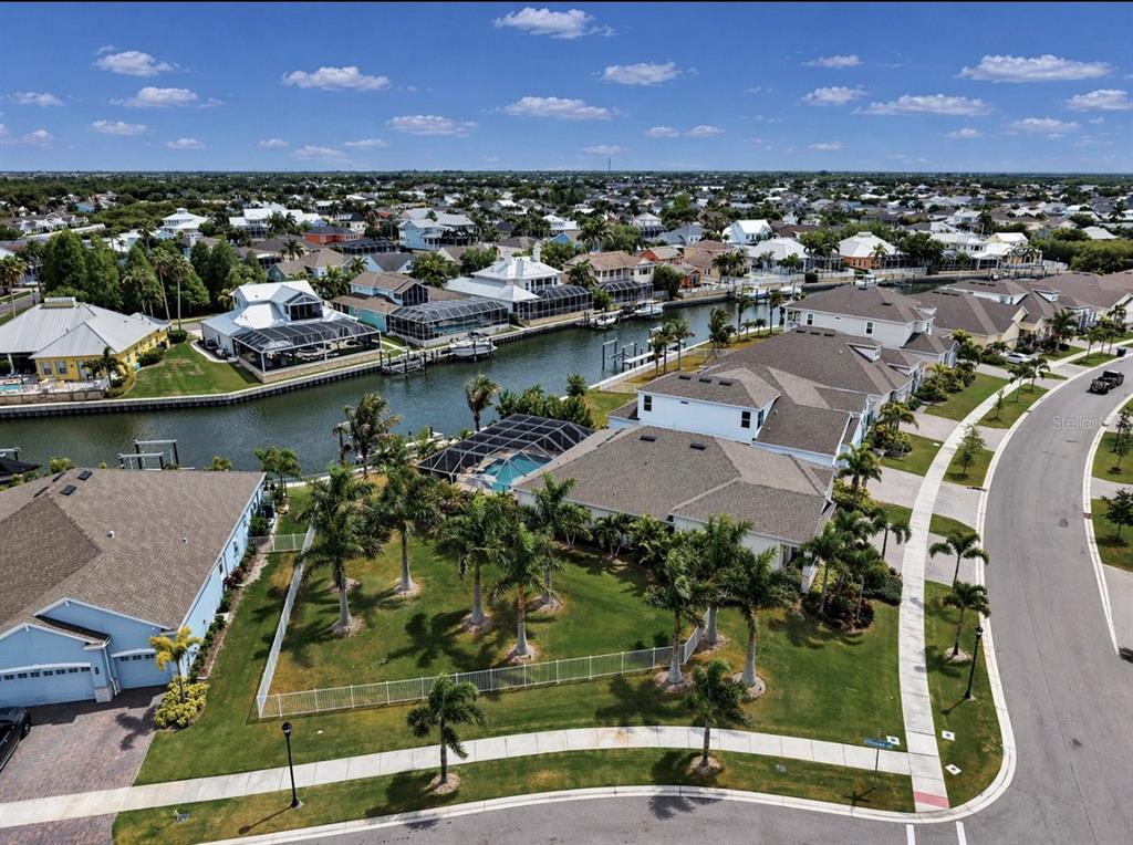 An aerial view shows waterfront houses with swimming pools and palm trees along a canal — 954 SIGNET DRIVE, APOLLO BEACH, FL