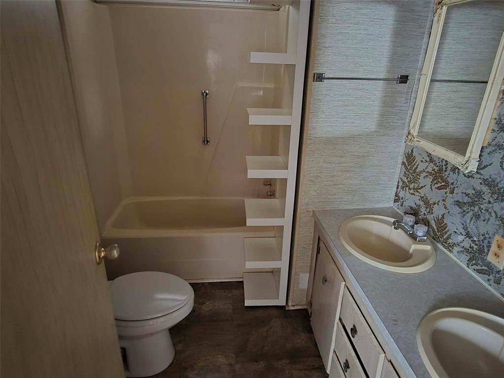 A bathroom features a tub-shower combo with built-in shelving, a toilet, and a double vanity — 5930 SW 61ST PLACE, OCALA, FL