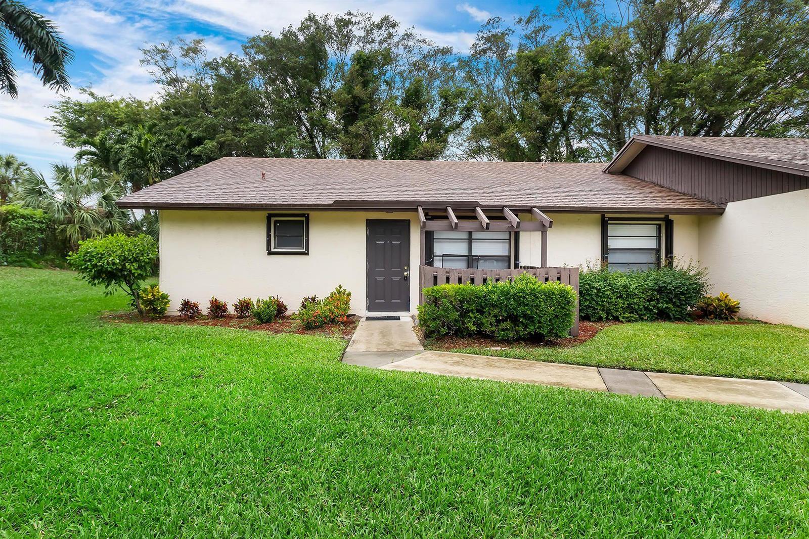 A single-story house exterior with a brown front door, pergola, and surrounding green lawn — 9 Vía De Casas Norte, Boynton Beach FL 33426, BOYNTON BEACH, FL