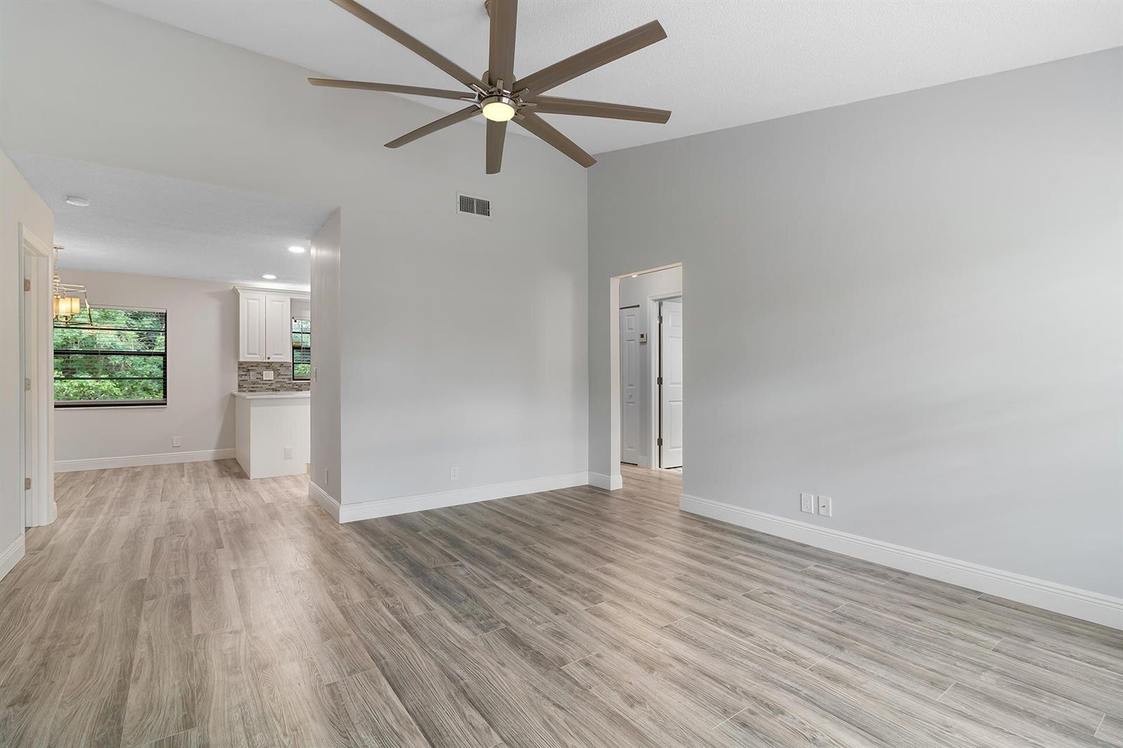 An empty room with light gray walls, wood-look tile flooring, and a large ceiling fan — 9 Vía De Casas Norte, Boynton Beach FL 33426, BOYNTON BEACH, FL