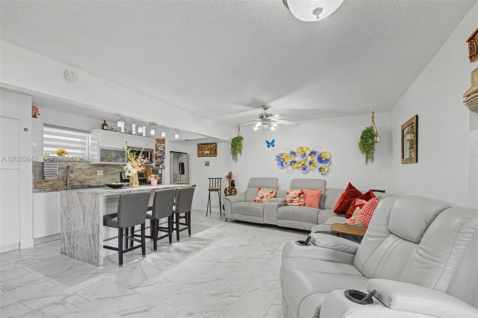 An open-concept living room and kitchen feature light gray tile floors and marble countertops — 399 NW 72nd Ave # 320, Miami FL 33126, MIAMI, FL